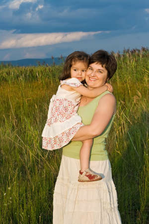 Happy young woman and her daughter staying outsideの写真素材