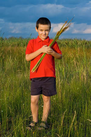 Happy little boy holding in his hands reedsの写真素材