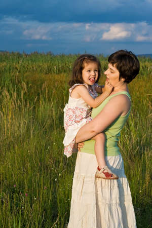 Happy little girl with her mother staying outsideの写真素材