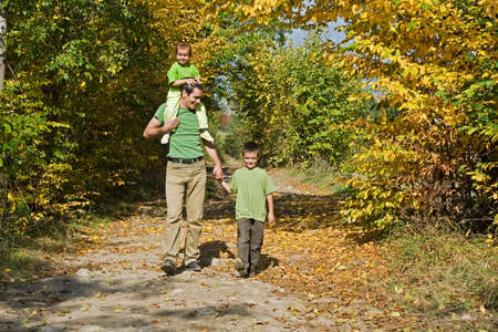 Father and his two children walking on the path during autumnの写真素材