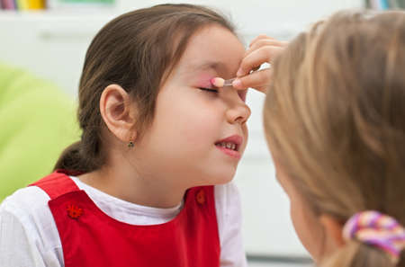 Little girl doing make-up to her girlfriendの写真素材