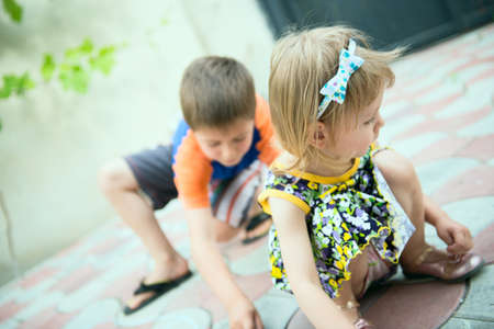Two children drawing by chalk on a sidewalkの写真素材