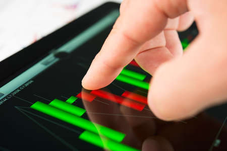 Businessman hand touching screen of tablet pc with market graphの写真素材