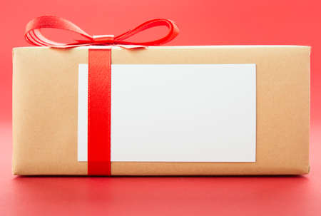 Wrapped gift box with red bow, isolated on red backgroundの写真素材