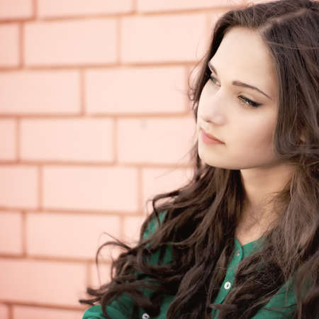 Young elegant woman in front of brick wall backroundの写真素材
