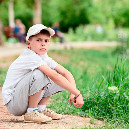 Portrait of boy sitting in a park squatの写真素材
