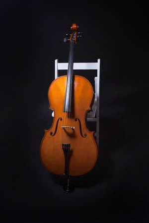 Cello leaning on white chair on black backgroundの写真素材