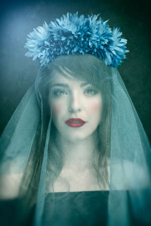 Mysterious woman behind blue veil on dark fantasy theme backgroundの写真素材