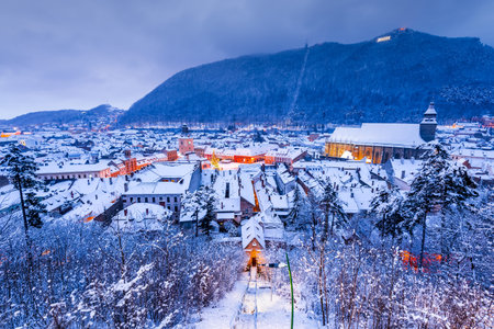 Brasov, Transylvania. Winter night scenery with Downtown and Carpathian Mountains. Travel background...