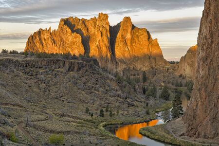 The Smith Rock area is made up of layers of recent basalt flows overlaying older Clarno ash and tuff formations. Approximately 30 million years ago, a large caldera was formed when overlying rock collapsed into an underground lava chamber. This created a huge amount of rock and ash debris that filled the caldera. That material eventually hardened into rock, becoming Smith Rock tuff. A half million years ago, basalt lava flows from nearby volcanoes covered the older tuff. Over time the Crooked River cut its way through these layers of rock. The river has an elevation of 2600 ft above sea level and the top of Smith Rock is 600 ft higher.の写真素材