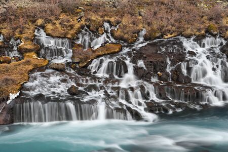 Water flowing from a large lava field into the river at Hraunfossar, Iceland.の写真素材