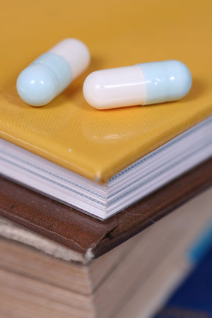 condensed knowledge - two pills on a stack of booksの写真素材
