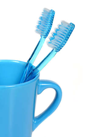 two blue toothbrushes in a blue cup over white backgroundの写真素材