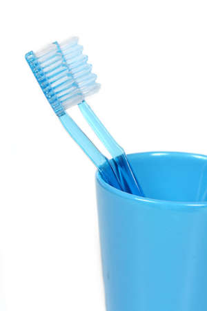 two blue toothbrushes in a blue cup over white backgroundの写真素材