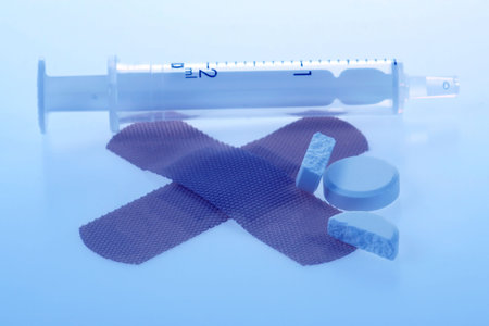 bandaids, pills and syringe with a blue tint