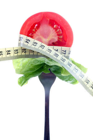 tomato slice and salad on fork with measure tapeの写真素材