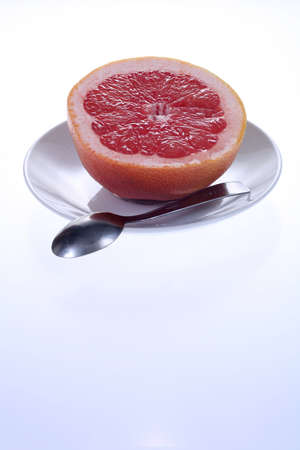 healthy breakfast - half of grapefruit on a plate with spoon isolated on white background, lots of copyspaceの写真素材