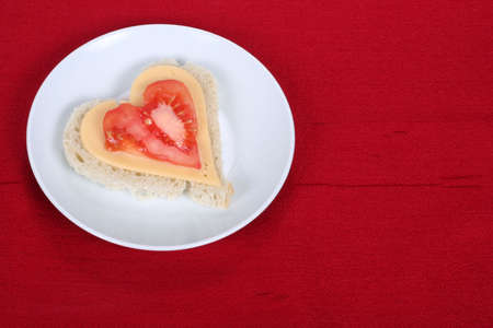 Heart shape sandwich on white plate, on red backgroundの写真素材