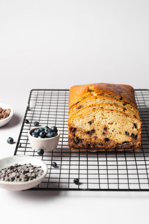 Vanilla cake with chocolate drops and blueberries on a culinary lattice, with ingredients on a light...