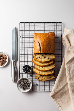 Top view vanilla cake with chocolate chip on a culinary lattice, with bowl of milk and dark chocolate drops and blueberry on a light gray background.の写真素材