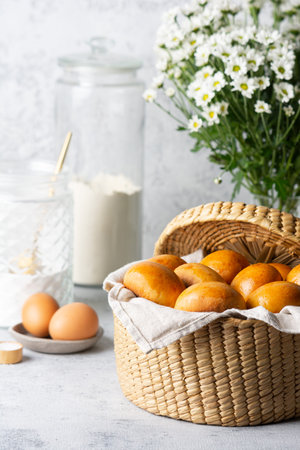Yeast baked patties with a golden brown crust in a wicker basket with ingredients and chamomile...