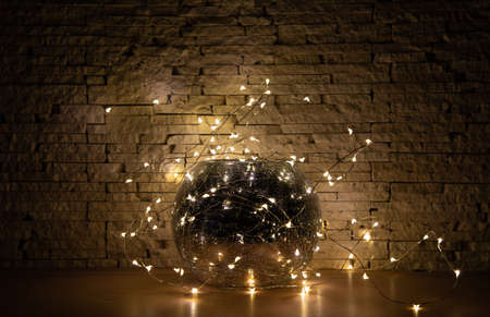 Garland lights around glass mirror vase on beige stone background.の写真素材