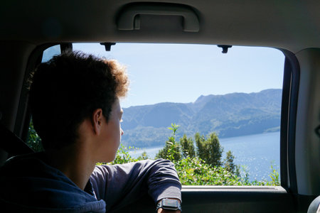 Young man traveling by car, looking out the window and enjoying the viewの写真素材
