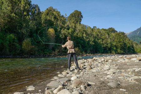 A young man fishing in a beautiful turquoise river in the south of Chileの写真素材