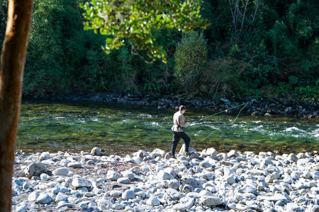 A young man fishing in a beautiful turquoise river in the south of Chileの写真素材