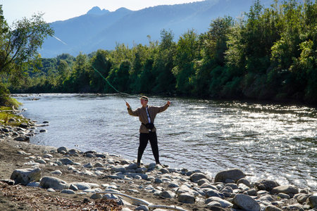 A young man fishing in a beautiful turquoise river in the south of Chileの写真素材