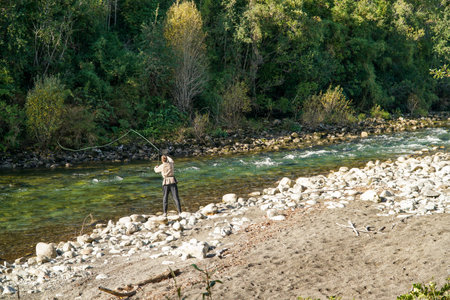 A young man fishing in a beautiful turquoise river in the south of Chileの写真素材
