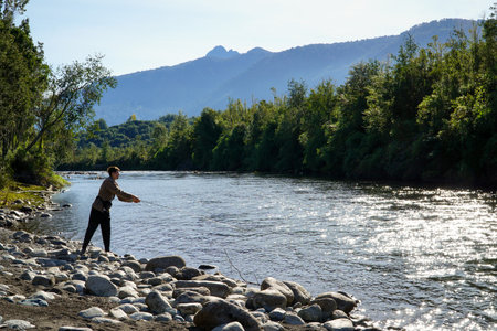 A young man fishing in a beautiful turquoise river in the south of Chileの写真素材