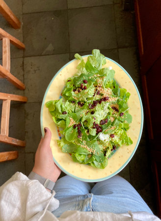 A person holding a plate with a big fresh saladの写真素材