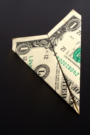 Dollar bill airplane on a black backgroundの写真素材