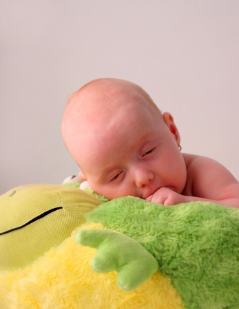 Baby girl falling asleep on top of a stuffed animalの写真素材