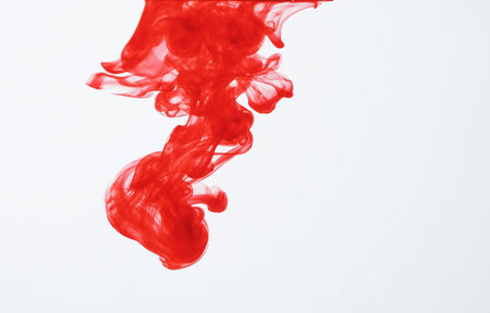 Red ink dispersing in waterの写真素材