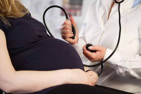 Pregnant woman having her blood pressure checked by the doctorの写真素材