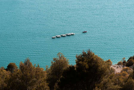 A boat navigates the turquoise blue water of a lake in Provenceの写真素材