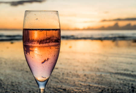 A drink in a glass in front of a sunset on an islandの写真素材