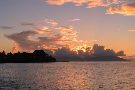 A house on stilts in front of sunset behind clouds