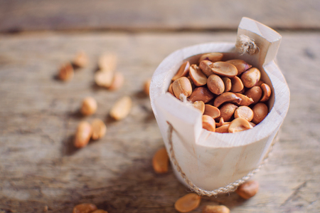 Peanuts in wooden bowl on wooden backgroundの写真素材