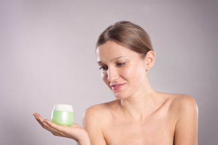 Happy young woman holding her favorite face creamの写真素材