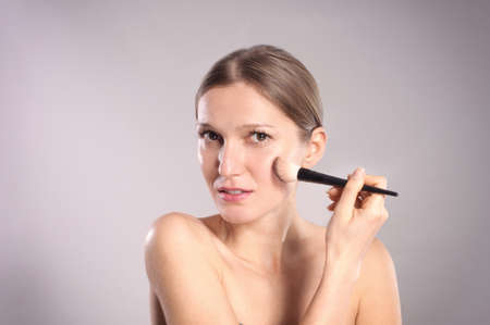 Young woman putting make-upの写真素材