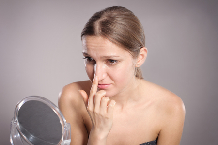 Young woman checks her nose in the mirrorの写真素材