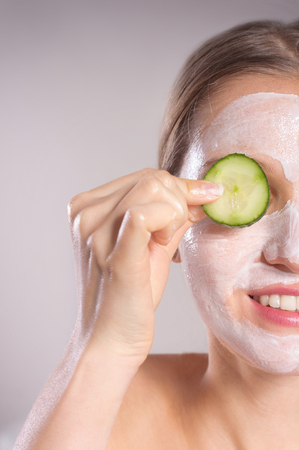 Beautiful young woman receiving facial mask of cucumberの写真素材