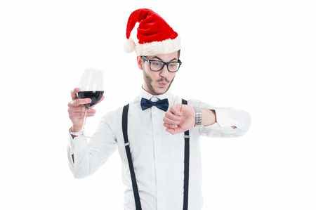 Young man with Christmas hat is looking at his watchの写真素材