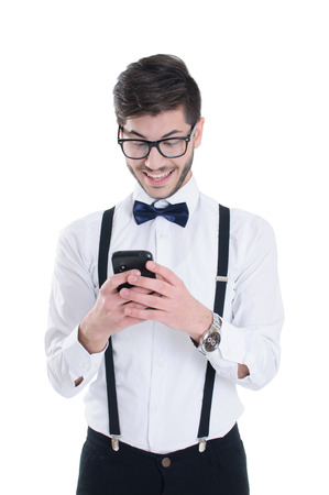 Smiling young man looking at his smart phone while text messaging isolated on white backgroundの写真素材