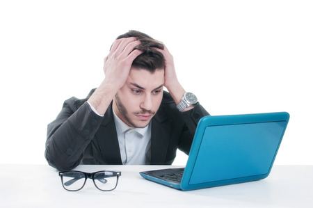 Young business man looking at his laptop with disappointment. Isolated on white backgroundの写真素材