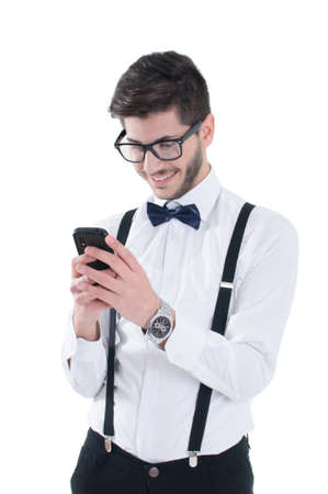 Smiling young man looking at his smart phone while text messaging isolated on white backgroundの写真素材