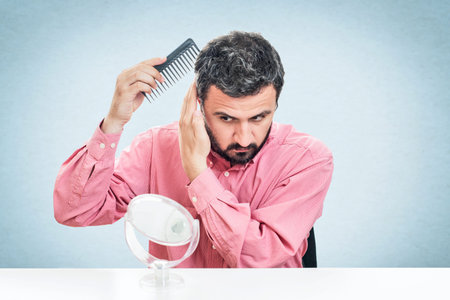 Handsome young beard man combing his hairの写真素材